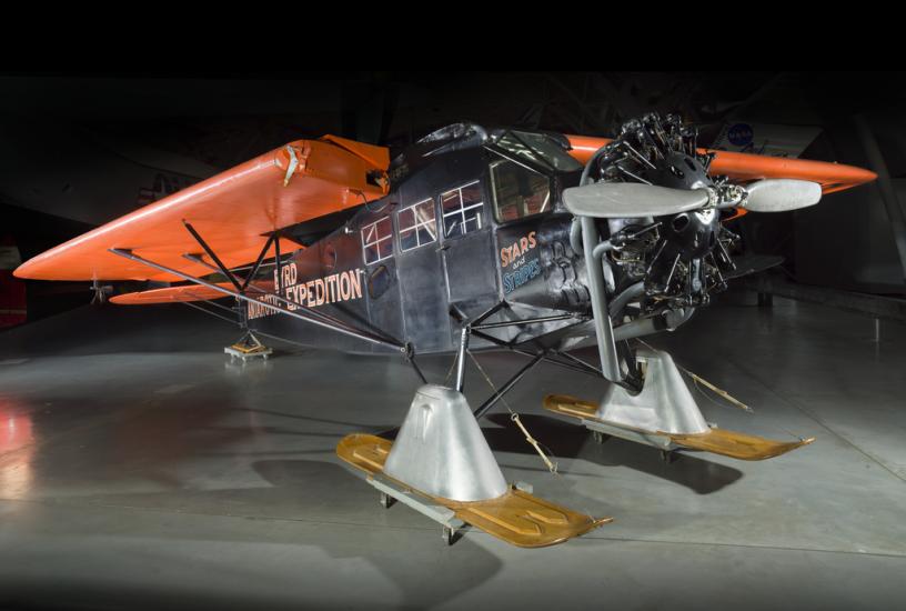 Black and orange painted plane with landing skis. 		