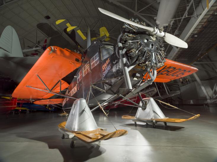 Black and orange painted plane with landing skis. 		