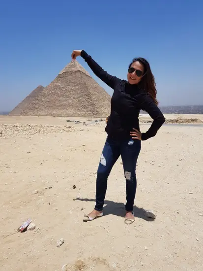 Pilot Shaesta Waiz in Egypt appearing to touch the top of a pyramid that's in the distance. 