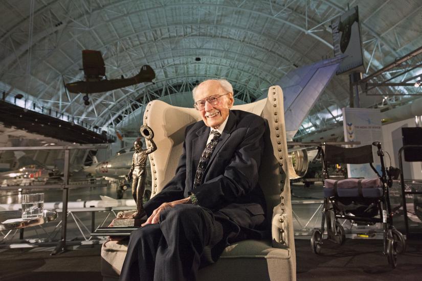 Bob Hoover sitting in a chair amongst the exhibitions at the Udvar-Hazy Center. 