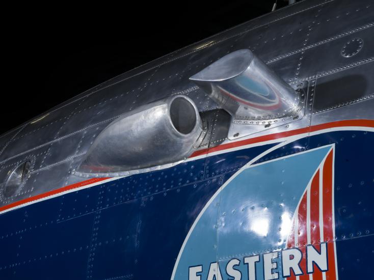 Close up of a silver painted exhaust valve on the fuselage of the plane. 