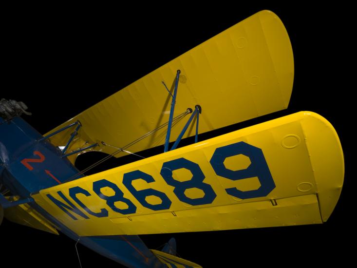 Yellow painted wings of an aircraft. NC8680 is painted on the wings on the aircraft. 