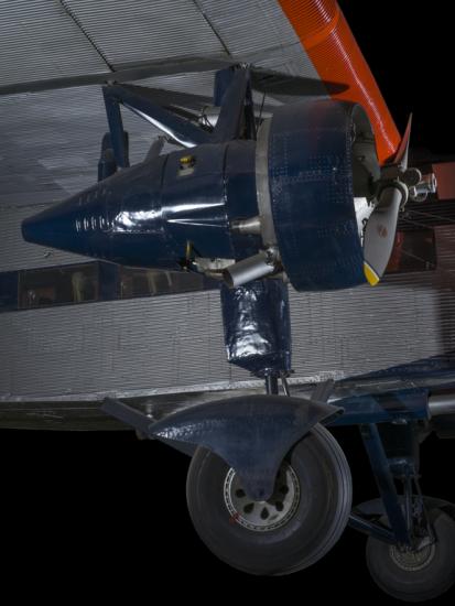 Blue painted engine of an airplane. In the background of the image is an aircraft. 