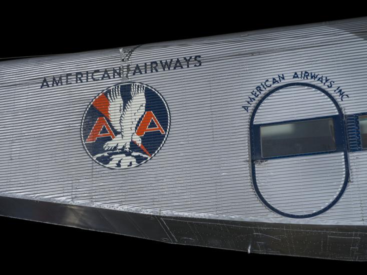 Silver painted fuselage of an airplane. Painted on to the fuselage is an American Airways logo.