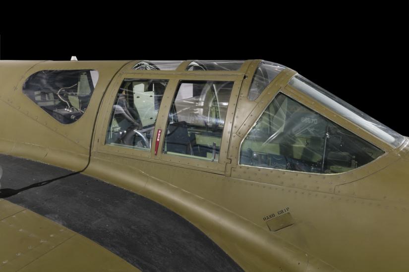 Close up view of a cockpit of a green painted jet aircraft. 