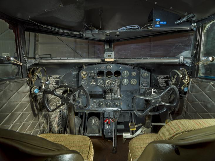 View of the interior cockpit of a plane. In this image are the Instrument panel, seats, and windows of a cockpit of a plane. 