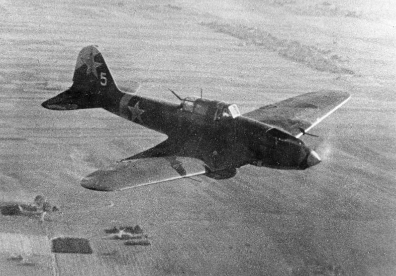 Airplane flies over what appears to be farmland. 