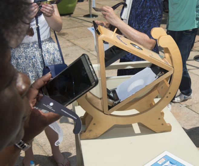 A projection of an eclipsed sun, in a crescent shape, on a triangular shaped device.