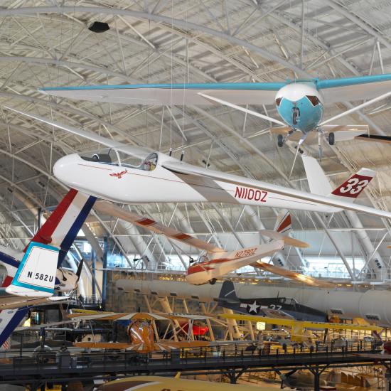 Full view of a streamlined red and white aircraft suspended from the ceiling. The number 33 is on the tail and the code NIIOOZ is on the side.