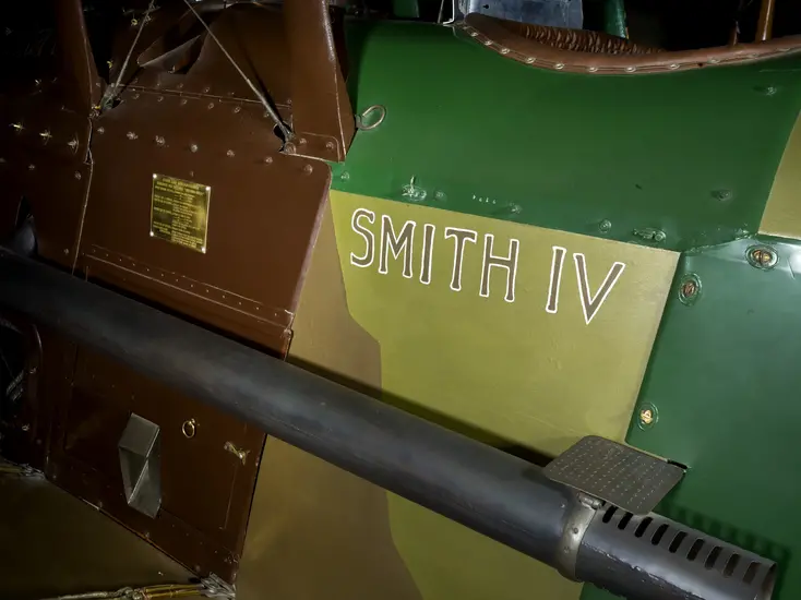 "Smith" in brown lettering on body of Spad XIII "Smith IV" aircraft. The aircraft is metal and painted different color greens.