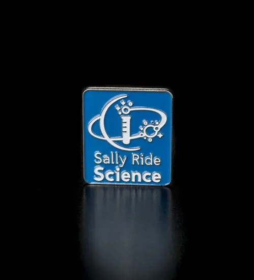Blue, enamel metal pin with tie tac clasp. Reads "Sally Ride Science." Also depicts image of test tube with rings and semicircle.