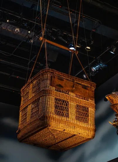 An acorn colored cane basket with miscellaneous rope and fittings suspended from the ceiling.  