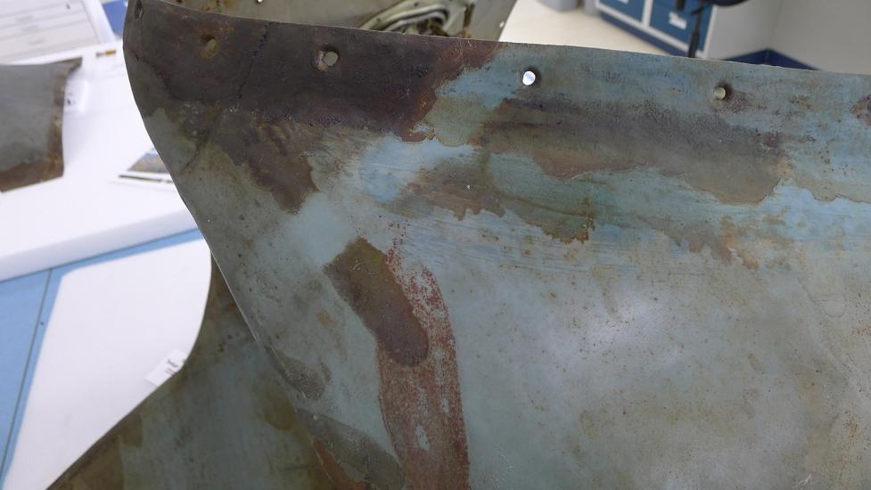 A section of the Horten Ho 229 V3 is tested to determine if a certain cleaning method will move a preservative coating. In this instance, a small strip of the section of the gray monoplane is significantly cleaner than before.