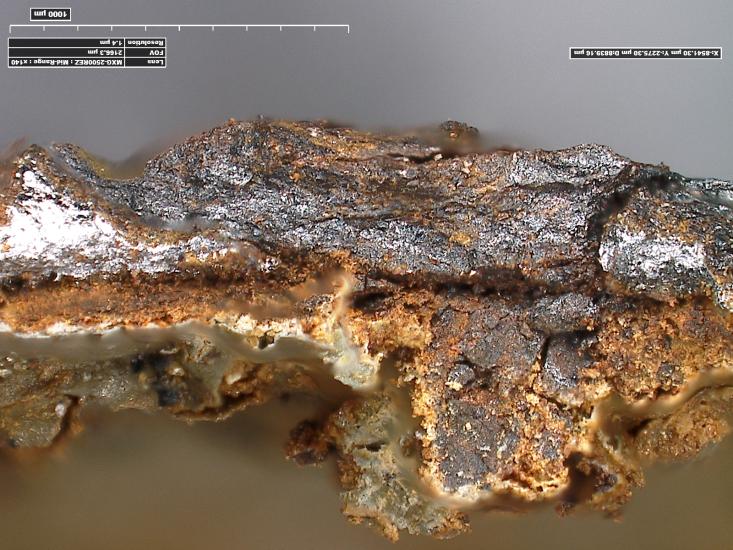 Microscopic, three-dimensional view of painted metal from a World War II-era aircraft. Corrosion is present on the bottom end, where loss of paint is present. The metal is still, however, in decent shape.