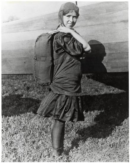 Tiny Broadwick, a white female parachutist, wears a back-pack parachute.