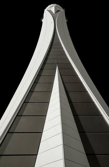 Partial view of the base of an air traffic control tower in Dubai. The base features a gray concrete stacking pattern with white ornate edges and details.