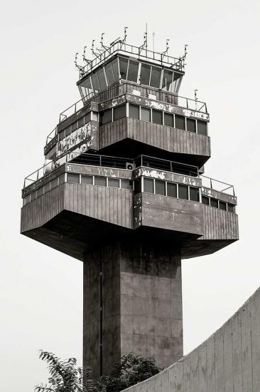 Partial view of the air traffic control tower at Barcelona El-Prat Airport. The tower features a steel base with three floors of operations, each floor smaller than the one before it.