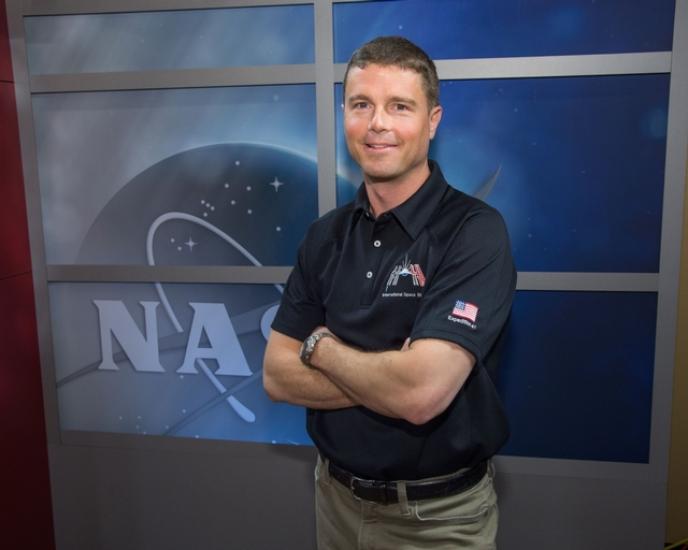 Reid Wiseman, a white male NASA astronaut, poses informally with his arms crossed.