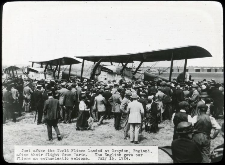 A large group of people view two Douglas World Cruisers, aircraft which were the first to travel around the world, in England.