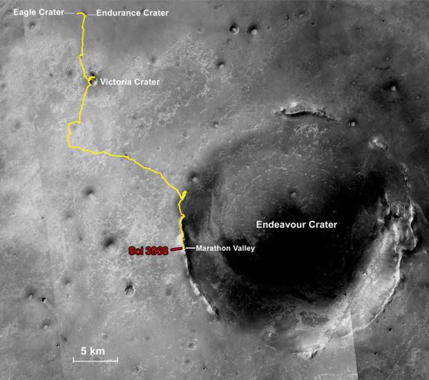 A partial, black and white satellite view of Mars with a yellow line describing the movement made by Opportunity, a Mars rover, between multiple craters.