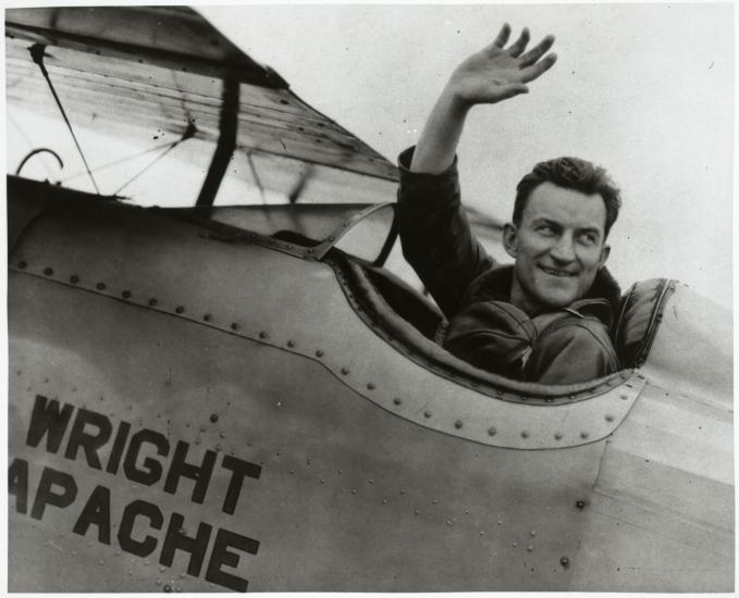 Lt. Apollo Soucek, a white male pilot, waves from the cockpit of an aircraft.