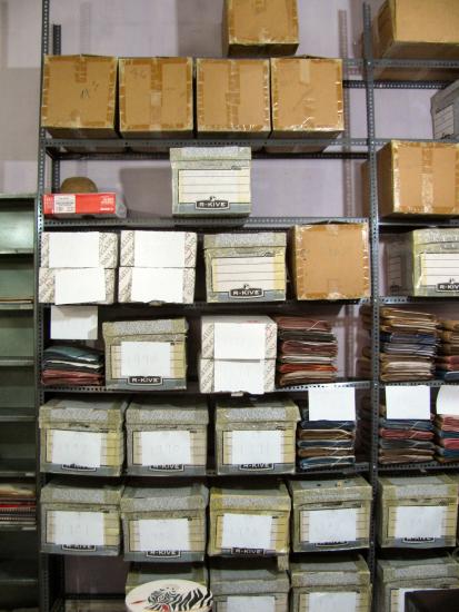 A multi-shelf storage display with twenty-one visible boxes and multiple other folders.