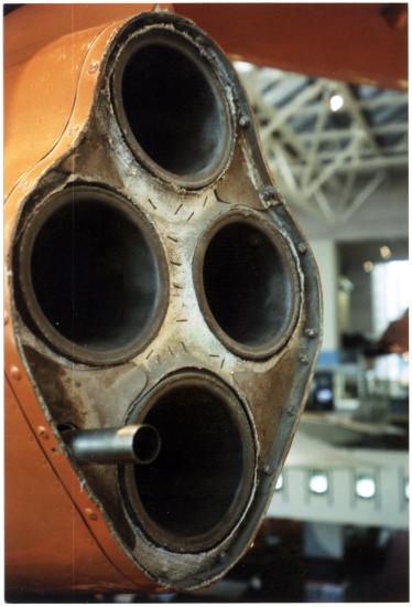 Front of four-rocket engine of orange military monoplane.