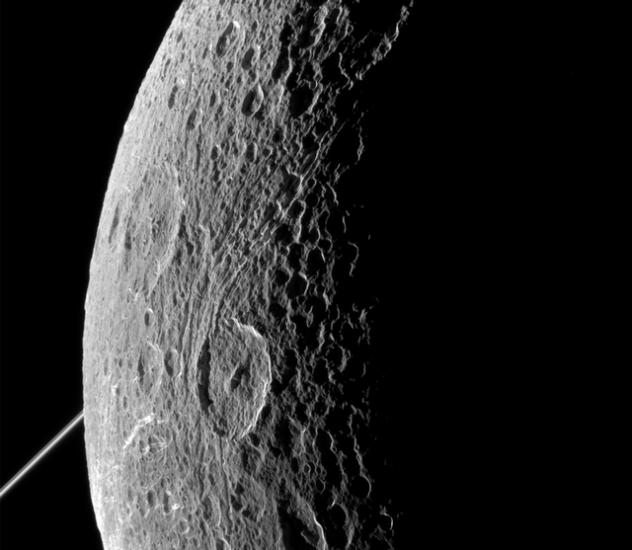 Partial view of a moon belonging to Saturn. The edge is lit by the Sun whereas the rest is facing away from the Sun.