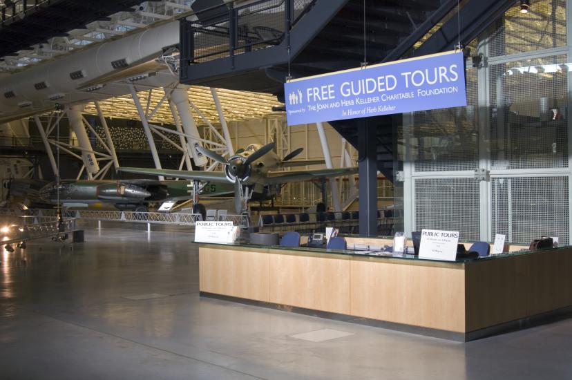 Diagonal front view of a guided tours desk inside the Steven F. Udvar-Hazy Center. The desk is located near a popular reconnaissance aircraft in the Museum's collection.