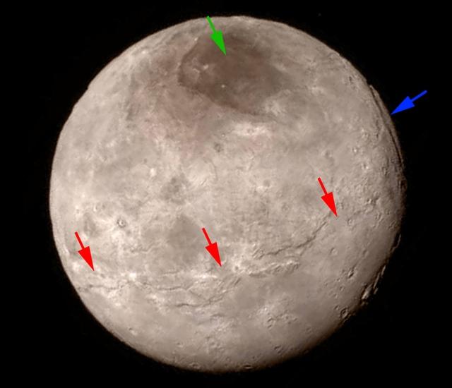 A disk view of Charon, Pluto's largest moon, which has a gray and brown color. Different colored arrows highlight various geographical features on the planet.