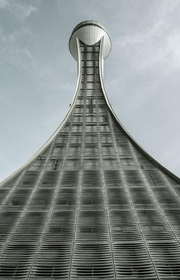 Air traffic control tower with a vial-shaped support structure that expands at the bottom from a narrow top. The support structure looks to be made from sections of steel.