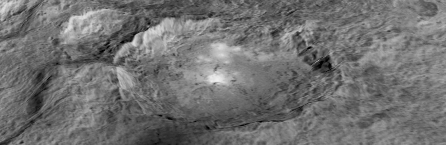 Black and white, close-up view of a large crater on Ceres, a dwarf planet. The crater has a shape similar to an oval.