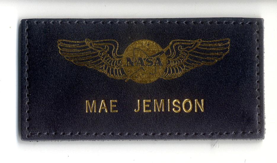 Black leather name tag with name "Mae Jemison" below NASA emblem with wings. The name and emblem are embossed in a golden color.