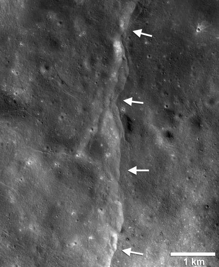 View of fault scarps, where land on one side has moved vertically, on the Moon. White arrows point out the fault line.