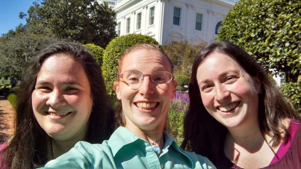 Three Museum educating staff members pose informally outside the White House.