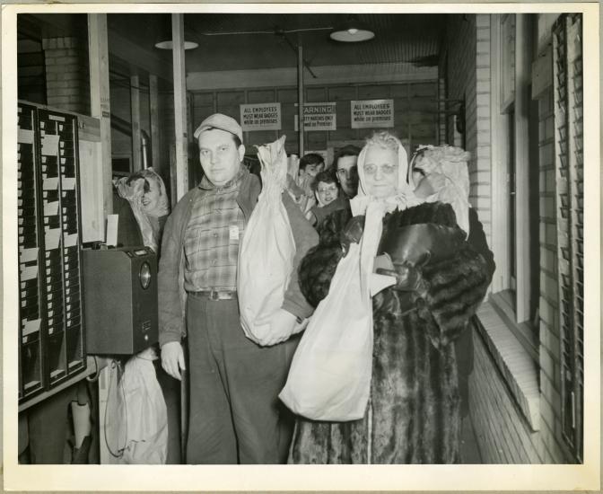 Multiple employees of an aeronautical corporation in the 1940s hold their bagged turkeys.