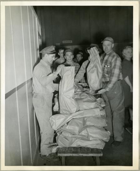 Employees of the Northwestern Aeronautical Corporation line up behind a stand of turkeys that are being given away.