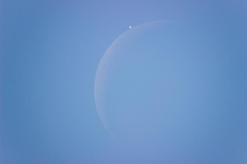 View of the daytime sky as the Moon is just about to block the view of Venus.