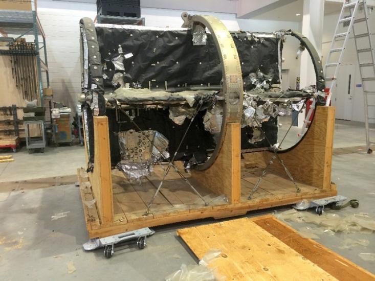 Side view of telescope mount spar, a telescopic object with a round-shaped base, prior to Museum restoration. The object is secutred to a wooden base and damage is seen to the black-colored material covering the center spar.