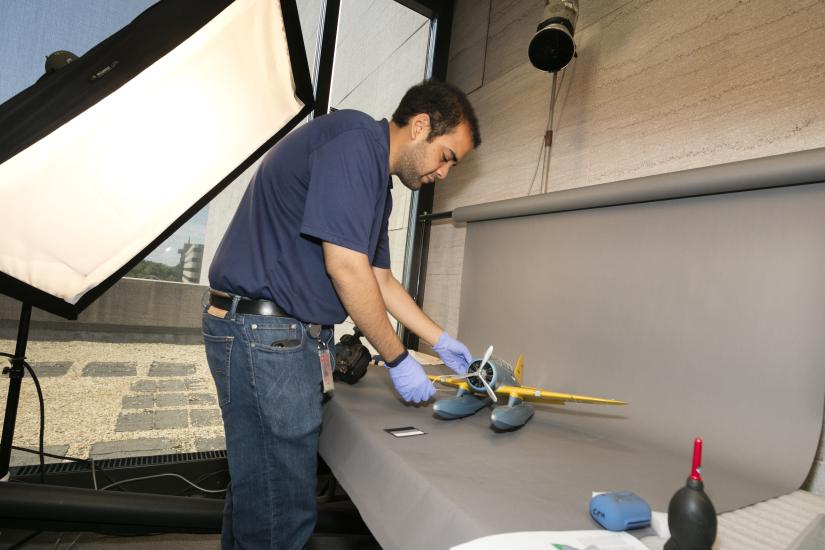 A Museum photographer moves an aircraft model prior to taking photos of the model.