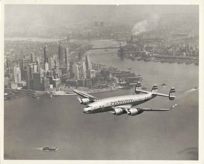 View of commercial aircraft in flight near a city.