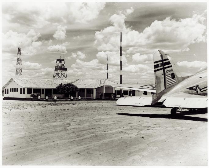 Part of the tarmac at Barreiras Airport in Brazil. Nearby are a one story building and the rear of a commercial aircraft.