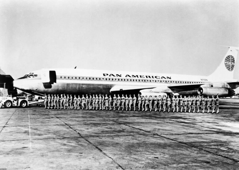 A group of Pan American Airways flight attendants board a commercial jet in a straight line.