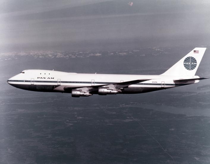 Black and white colored side view of aircraft with four engines and Pan Am Airways livery. Aircraft is in flight.