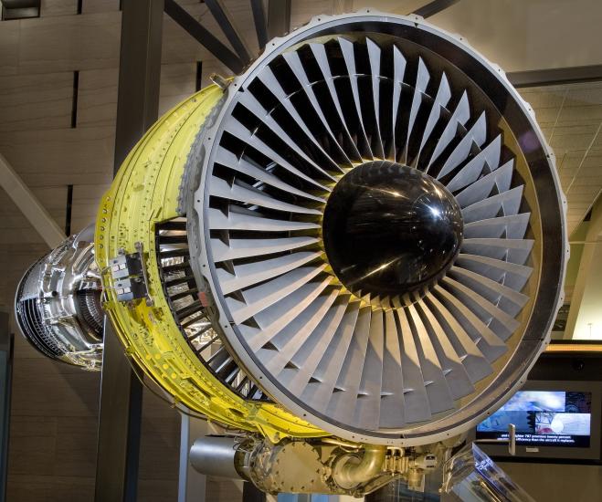 Front view of turbofan engine with large number of blades circling around a black, metal center.