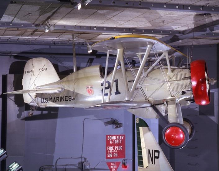 A silver biplane with red wheels and a red circle from which the propeller is mounted. The words "U.S. Marines" are on the side.