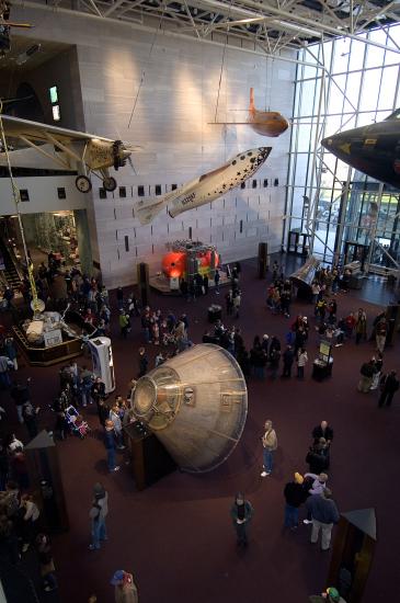 A museum exhibit with aircraft and spacecraft scattered across the floor and attached to the ceiling.