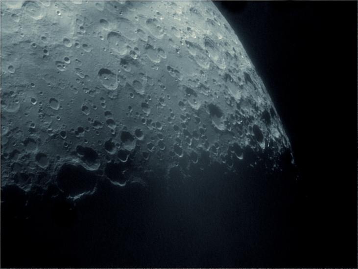 Partial view of the Moon with many craters visible.