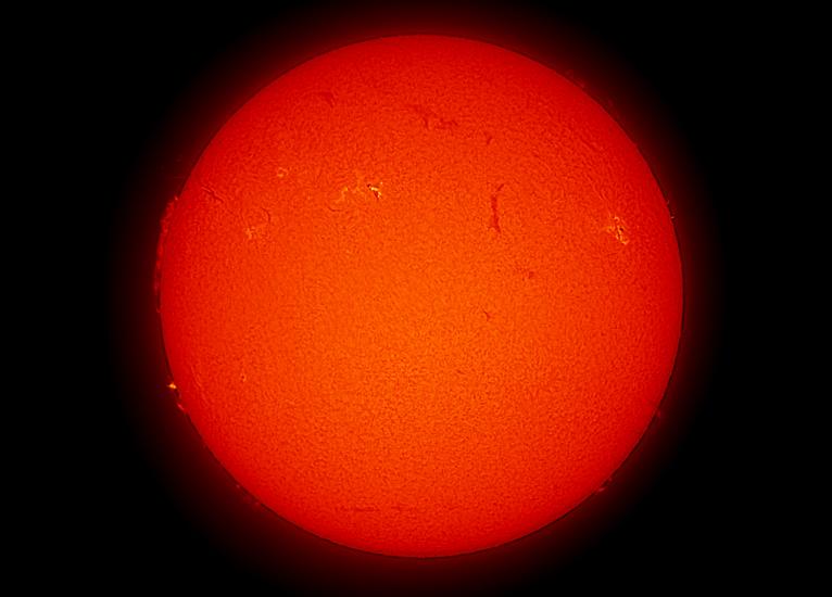 Disk view of the Sun with two visible sunspots and a large prominence of plasma rising from the Sun's surface on the left side of the disk.