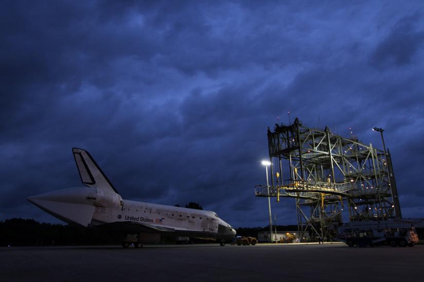 The Space Shuttle Discovery sits prior to being secured onto an aircraft via a large securing object known as a mate-demate device.